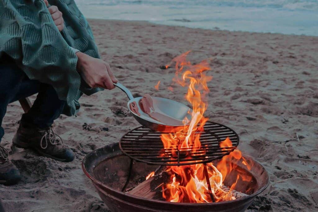 Scenic Cookout - Cooking bacon over a campfire on the beach.