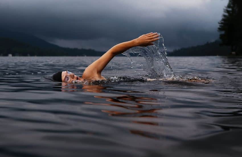 Woman swimming in lake beneath dark grey clouds