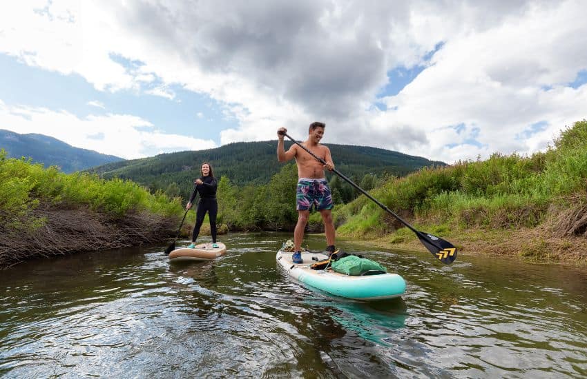 Couple paddle boarding on river