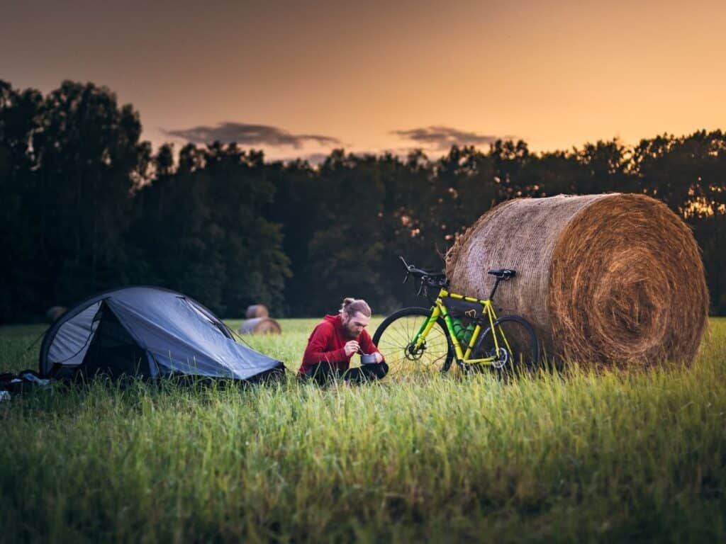 Is wild camping legal? Man camping behind hay bale.