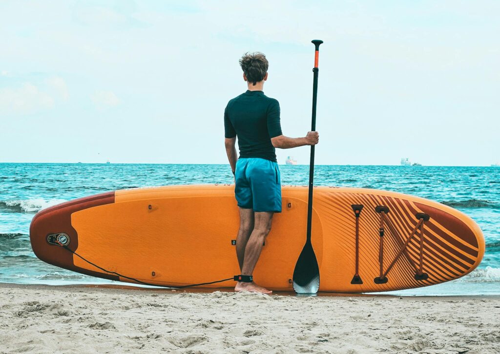 Mastering the Waves: How to Choose a Paddleboard 1 Man with Paddle Board on the Beach